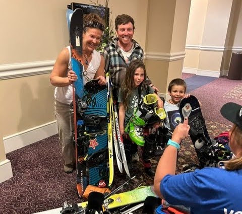 Family smiling with new ski and snowboard gear at the Crested Butte’s annual Gear Swap