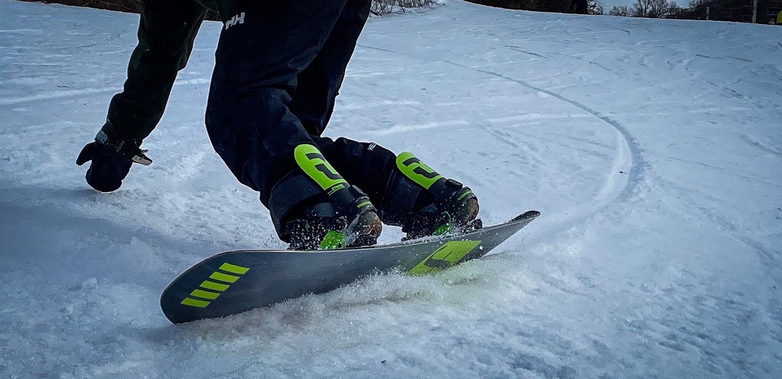 A snowboarder laying down a carved turn