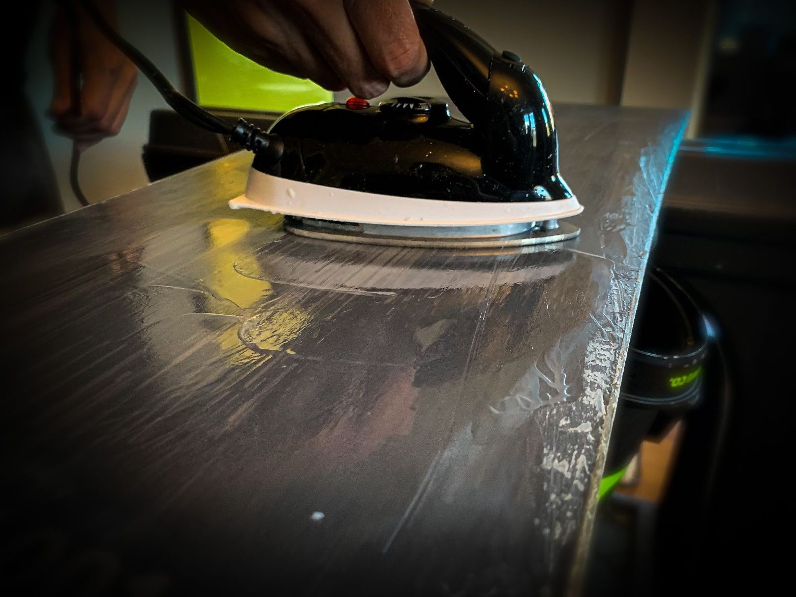 Waxing a snowboard using a waxing iron to melt and spread the wax on the snowboard base.