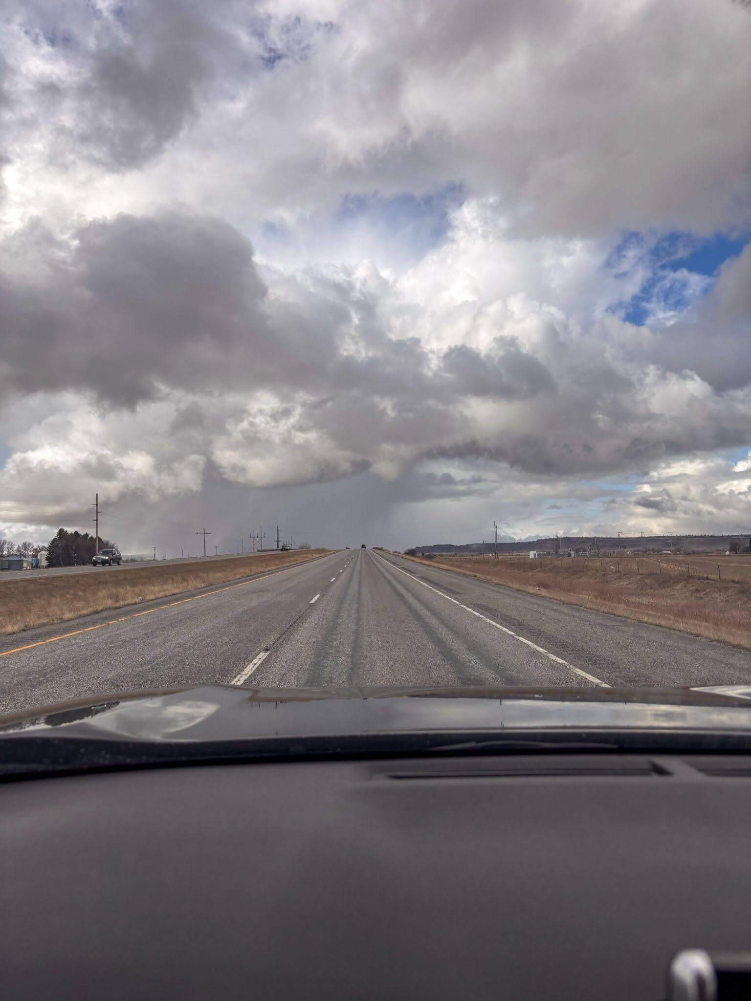 Looking out the front windshield on a long straight road in North Dakota